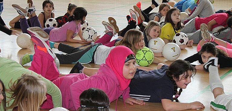 Kinder liegen mit Bällen auf dem Boden