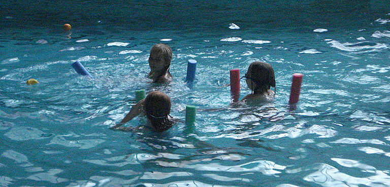 Mädchen im Wasser mit Schwimmnudeln