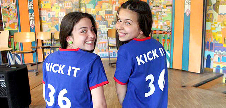 zwei Mädchen mit blauen Shirts und dem Logo Kick it drauf
