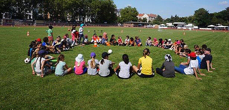 Kinder sitzen im Kreis auf dem Rasen